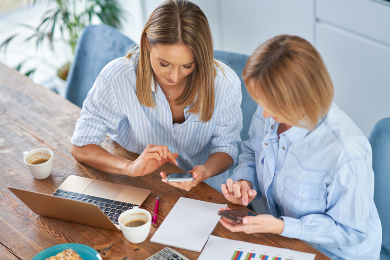 Two girl friends or lgbt couple with computer and invoice