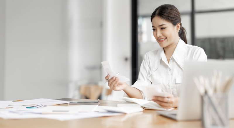 Happy beautiful woman paying bills on his laptop in home office